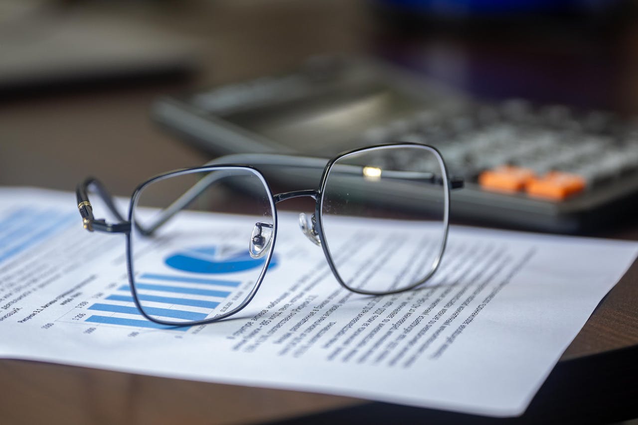 Eyeglasses on financial report with calculator in office setting, highlighting analysis.